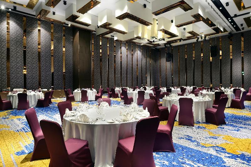 Caesar Park Hotel Banqiao Taipei Exterior photo The photo shows a spacious banquet hall or event space. The room features several round tables, each covered with white tablecloths, set up with place settings. The chairs around the tables are covered in deep burgundy fabric. The flooring has a colo