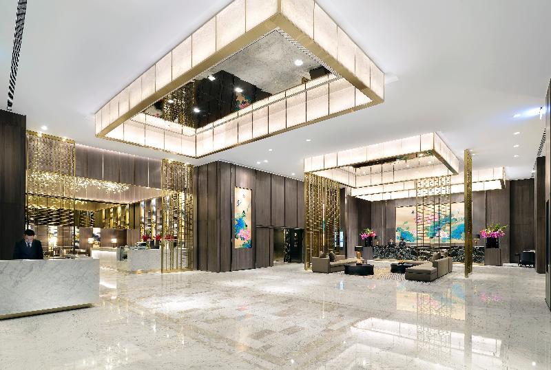 Caesar Park Hotel Banqiao Taipei Exterior photo The image shows a modern and elegantly designed hotel lobby. The space features high ceilings with decorative light fixtures hanging from above, providing a bright and welcoming atmosphere. The reception area is seen on the left, with a sleek marble 