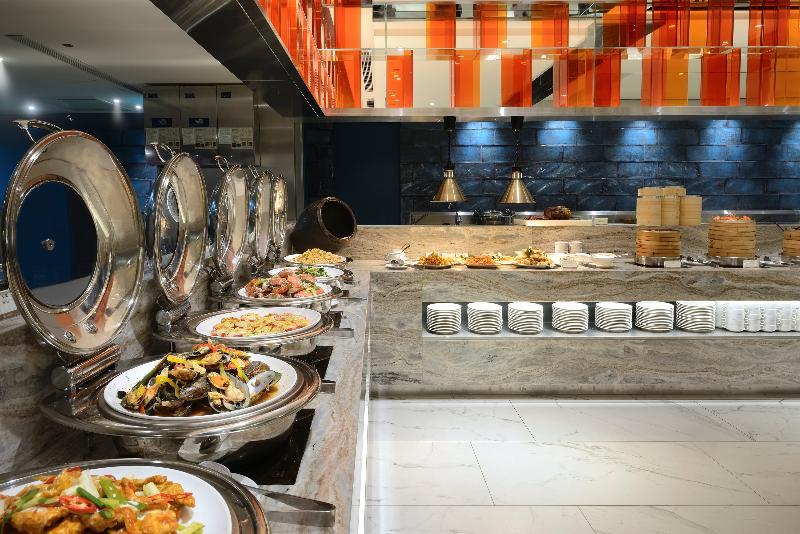 Caesar Park Hotel Banqiao Taipei Exterior photo The photo shows a dining area featuring a buffet setup. There are several large, silver chafing dishes arranged along a counter, each containing different types of food. The layout suggests a variety of dishes, likely including vegetables, meats, or 