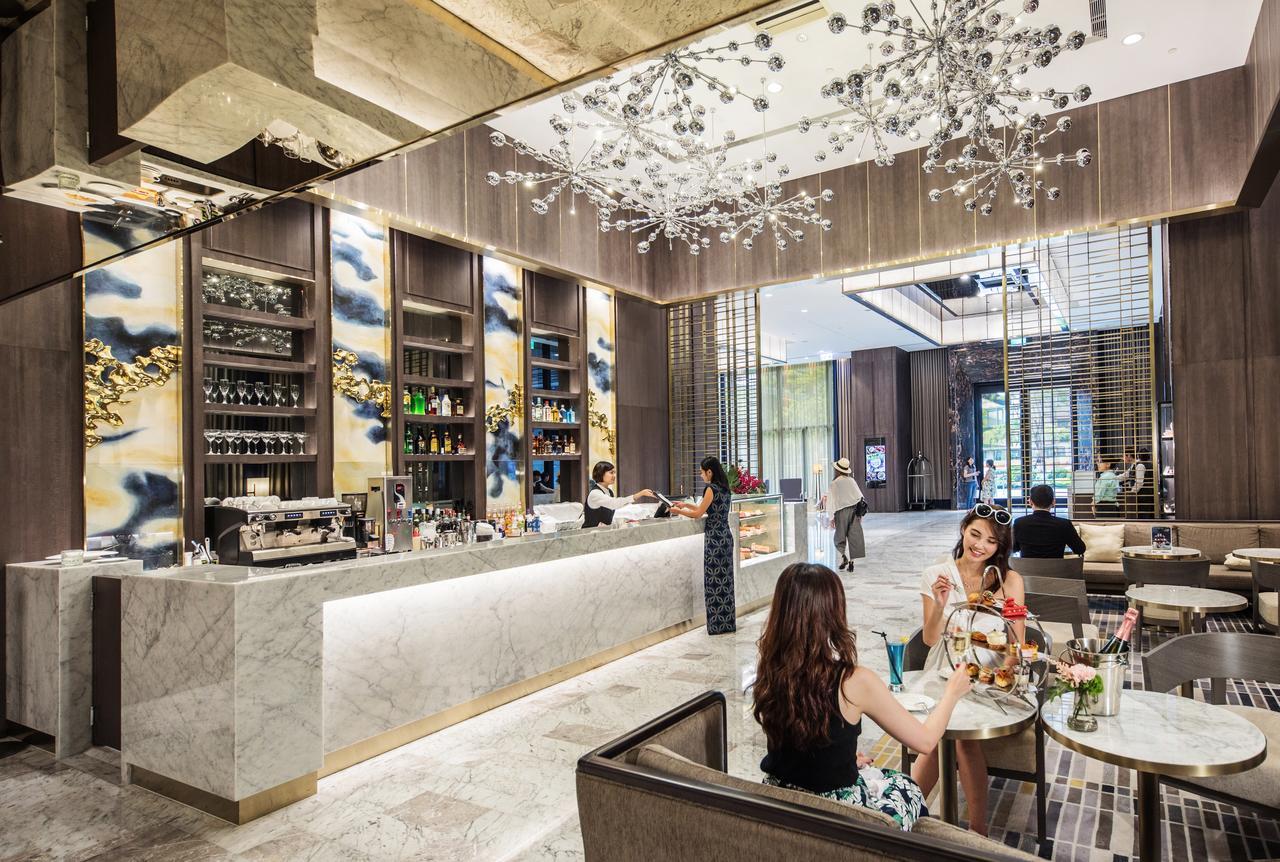 Caesar Park Hotel Banqiao Taipei Exterior photo The photo depicts a modern and stylish interior of a café or restaurant. In the foreground, several guests are seated at a table, enjoying drinks and meals. They appear to be engaged in conversation. Behind them, a sleek marble counter can be seen, w